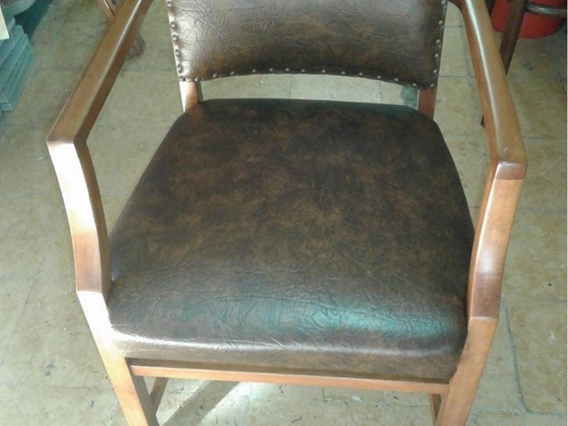 Silla de madera con asiento y respaldo tapizados en cuerina marrón con tachas