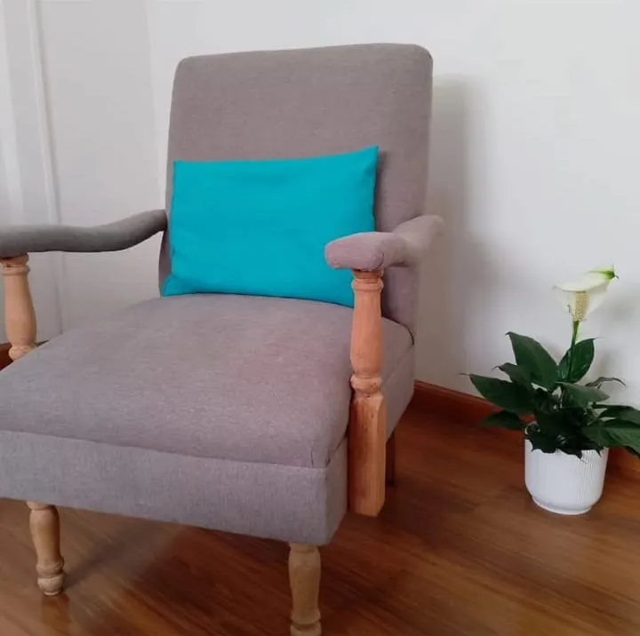 Sillón individual en tela gris con brazos y patas de madera torneada
